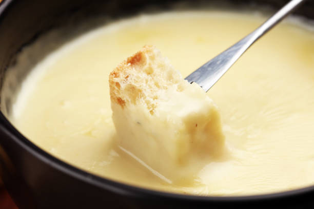 istock Gourmet Swiss fondue dinner on a winter evening with assorted cheeses on a board alongside a heated pot of cheese fondue with two forks dipping 1171066264