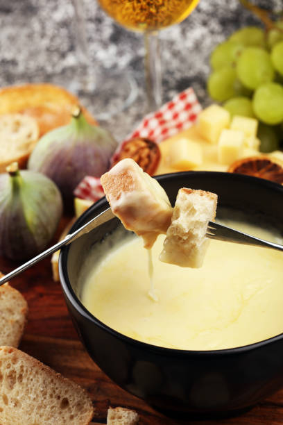 istock Gourmet Swiss fondue dinner on a winter evening with assorted cheeses on a board alongside a heated pot of cheese fondue with two forks dipping 1171067236