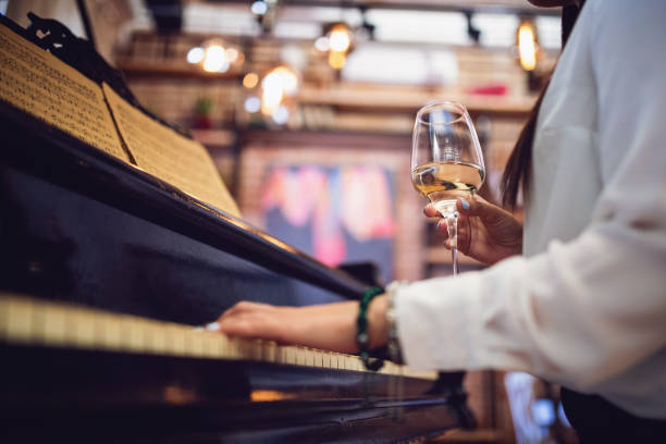 una pianista femenina tocando y bebiendo vino en un restaurante - pianist grand piano piano playing fotografías e imágenes de stock