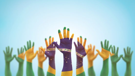 Bandera de Brasil en las manos de palma de la gente levantándose como voluntario, votando, ayuda deseada, y celebración de vacaciones nacionales rezando por el poder brasileño aislado en el fondo del cielo azul (ruta de recorte) photo