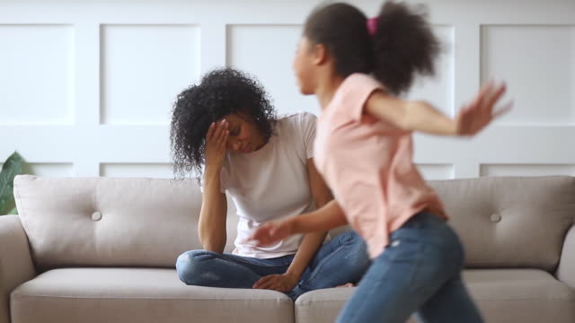 Upset african single mother feeling stressed about active noisy children