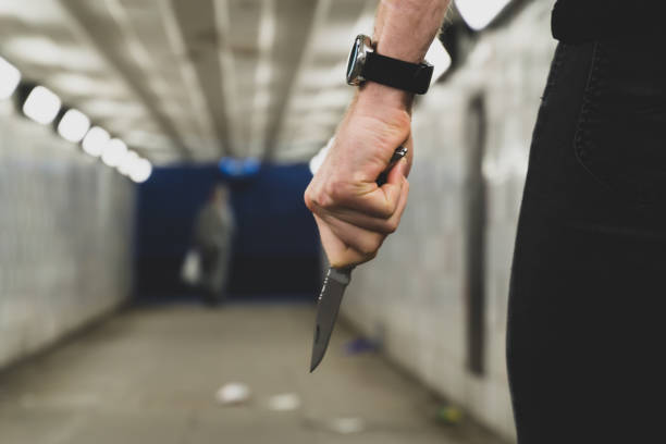 Crime and security concept - a thief with a knife is going to attack and rob another person in a tunnel Crime and security concept - a thief with a knife is going to attack and rob another person in a tunnel. knife weapon photos stock pictures, royalty-free photos & images