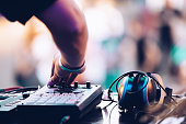 Concert dj playing electronic music set on stage at outdoor summer festival with drum machine device