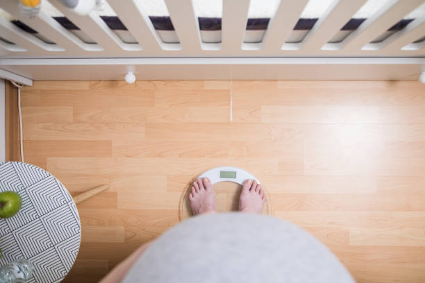 pregnant woman standing on scales top view. controlling weight gain on pregnancy time - mother exercising baby dieting imagens e fotografias de stock