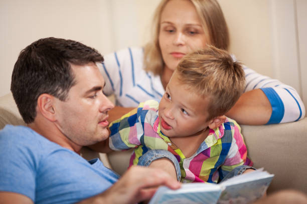 istock Curious little boy with mum and dad. Reading book together 1171082885