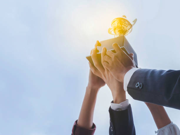 the best team helped each other reach their goals target to success. the hand of a business man and business women pick up the trophy and celebrate together. teamwork of successful concept - trophy imagens e fotografias de stock