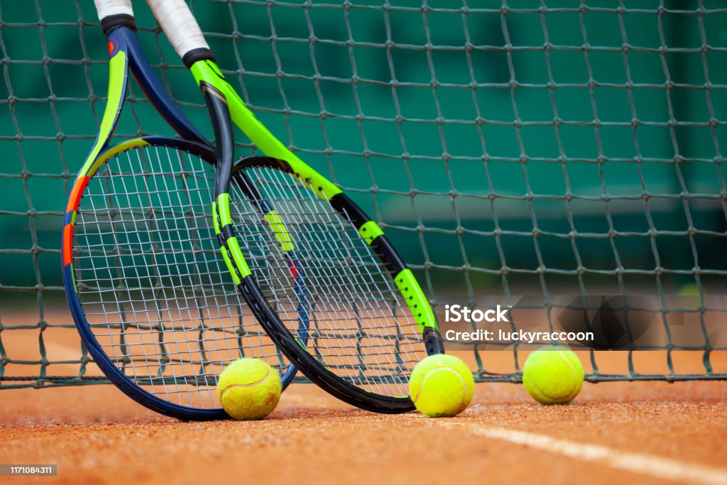 Tennis rackets and balls leaned against the net. Two tennis rackets and balls leaned against the net. Tennis Stock Photo