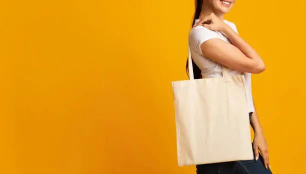 Photo of Millennial Girl Carrying Blank White Eco Bag Over Yellow Background