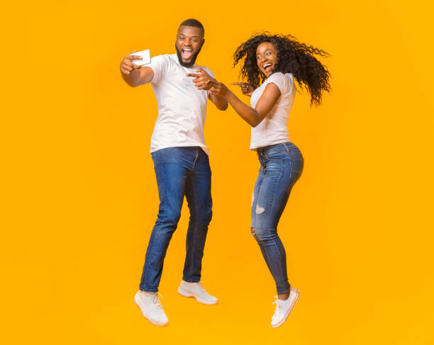 istock Lovely black guy and girl taking selfie while jumping 1171086005