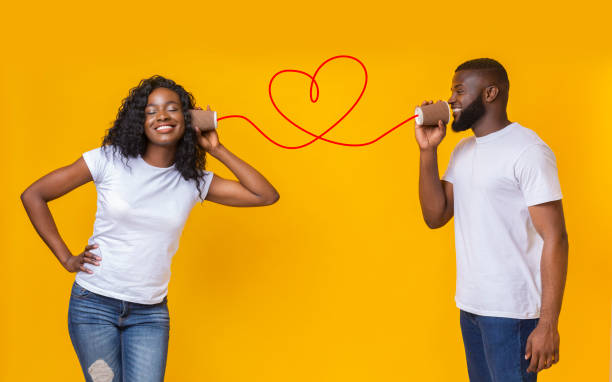 Young black couple with can phone on yellow background