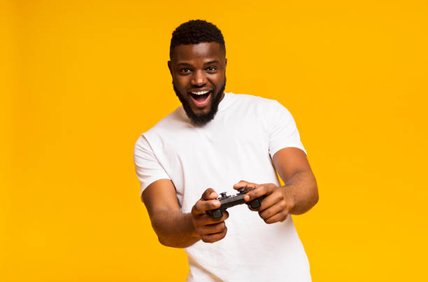 felice uomo afroamericano che gioca ai videogiochi con joystick - people joy relaxation concentration foto e immagini stock