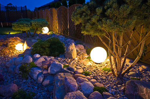 Home garden at night, illuminated by globe shaped lights. Decorative gardening and landscaping abstract.