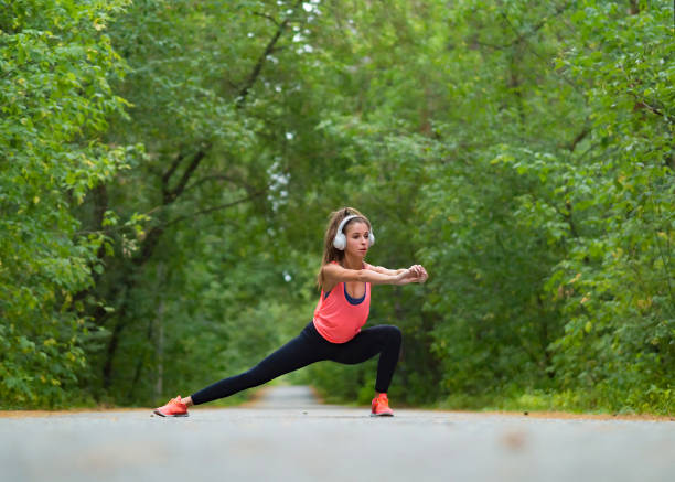 Woman stretch muscles at park before jogging. Athletic exercising outdoor. stock photo