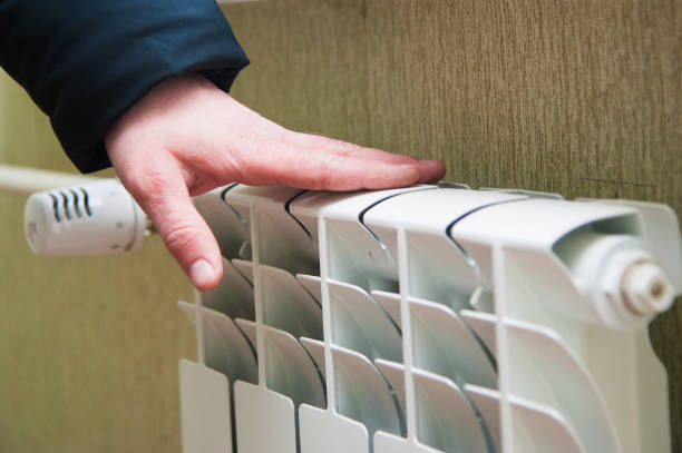 istock Hand adjusting the knob of heating radiator 1171094294