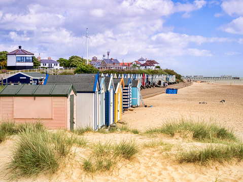 17 June 2019: Southwold, Suffolk, UK - The beach and beach huts, with the pier behind, at Southwold, Suffolk