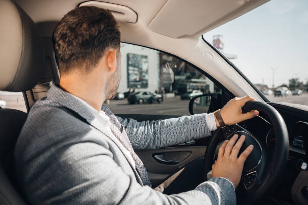 o homem de negócios bem sucedido em um terno conduz seu carro luxary. - luxary - fotografias e filmes do acervo