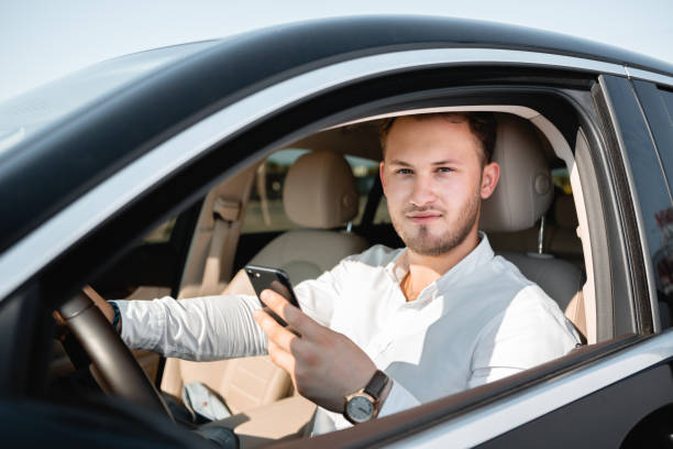 istock Young businessman smiling looking at mobile phone while driving a car. 1171096966