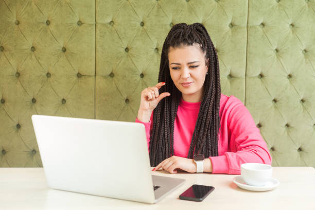 peu! verticale de jeune fille attirante avec la coiffure noire de dreadlocks sont assises dans le café, travaillant et faisant l'appel vidéo sur l'ordinateur portatif, compagnon heureux de donner plus de temps avec le joli visage. - less fortunate photos et images de collection