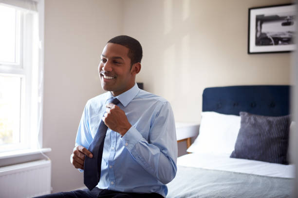 Young Man Getting Dressed In Bedroom For First Day At Work In Office Young Man Getting Dressed In Bedroom For First Day At Work In Office getting dressed stock pictures, royalty-free photos & images