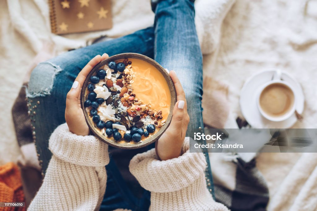 Woman holding a pumpkin smoothie bowl Pumpkin pie smoothie bowl topped with berries, granola, and coconut flakes Bowl Stock Photo