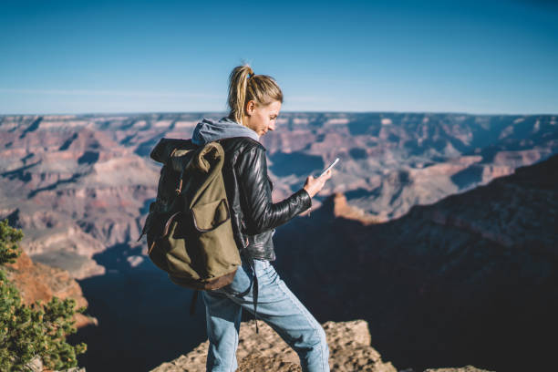 istock Smiling female american tourist read message on smartphone satisfied with good data connection in mountains, woman with backpack looking at cellular in hand standing on cliff hiking in wild nature 1171120179