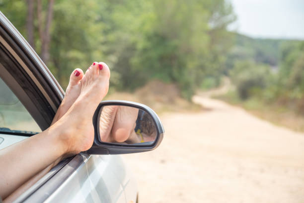 istock lady bare feet through the car window on the road 1171123208