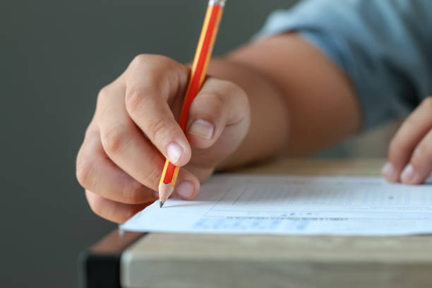 istock test exam for education in school concept : University student holding pencil notes paper on answer sheet at lecture chair for taking exams in examination classroom. Assessment learning in class ideas 1171123214