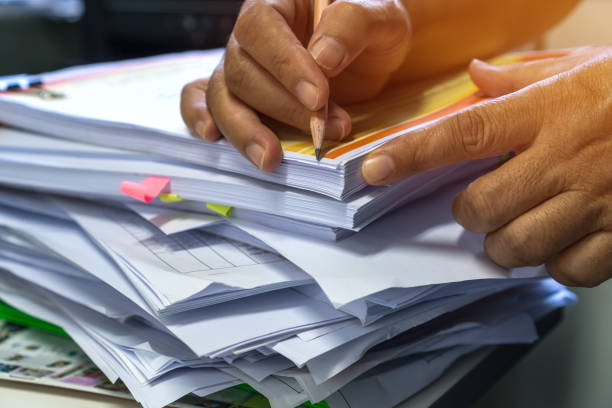 Business documents paperwork overwork concept : Employee people hands working in stacks paper files for searching and checking unfinished document report on folders print at busy work desk office concepto de exceso de trabajo de documentos empresariales : las personas de los empleados trabajan en pilas de archivos de papel para buscar y comprobar el informe de documentos inacabados en carpetas impresas en la oficina de escritorio ocupado