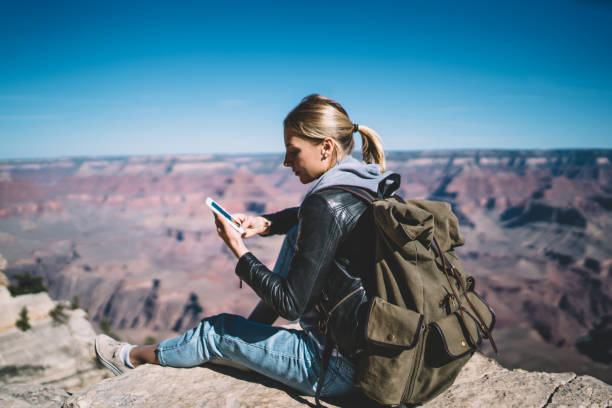 istock Young female tourist satisfied with mobile data network in mountains sending message on telephone resting on cliff,hipster girl wanderlust using application on smartphone for navigate during hiking 1171124263