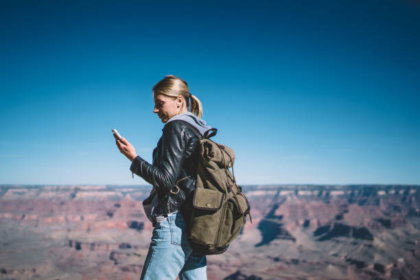 istock Young girl wanderlust with rucksack getting notification on telephone using data roaming connection during hiking tour,female traveler reading new message on cellphone standing on top in Grand canyon 1171124292