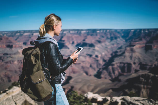 istock Positive hipster girl wanderlust with smartphone good connection for sending data during weekends in Grand canyon, smiling female hiker looking at breathtaking nature landscape holding cellphone 1171124300