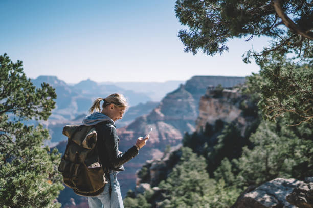 istock Smiling female tourist with backpack satisfied with having roaming mobile connection for communication in wild environment, hipster girl navigating during hiking tour using application on smartphone 1171124309