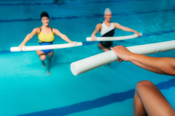 classe do aerobics de água, grupo de mulheres que exercitam com instrutor - people recreational pursuit exercising physical activity - fotografias e filmes do acervo