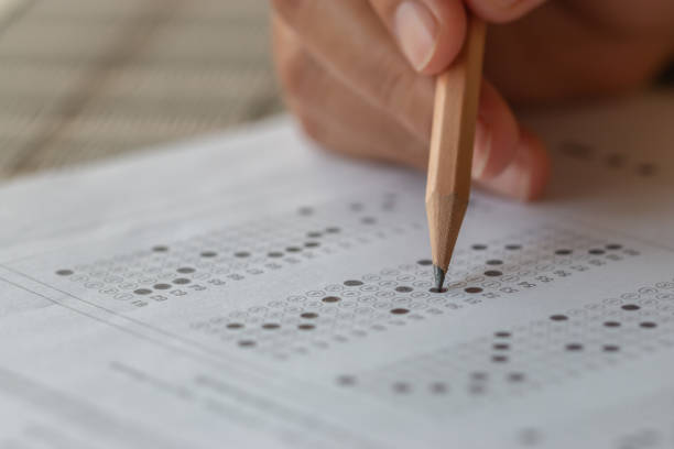 istock Student hand testing doing test exam with pencil drawing selected choices on answer sheet in school final exams at college or university. Taking multiple choice for assessment in examination classroom 1171126967