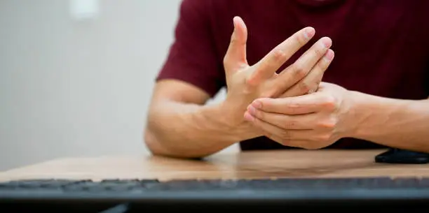 Photo of close up freelancer man use hand to massage for relief pain from hard working at office table ,carpal tunnel syndrome concept