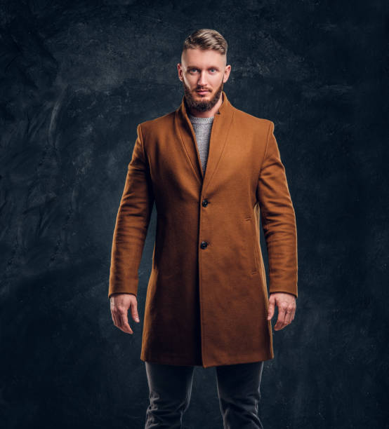 portrait of a stylish male wearing the demi-season coat. men's beauty, seasonal fashion. studio photo against a dark wall background - fashion men fashion model male imagens e fotografias de stock