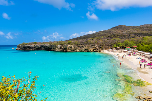 Tourists enjoying a beautiful sunny day on Kenepa Grandi, the bigger of the two beaches forming Playa Kenepa, two amazing sites located in the north of the Caribbean island of Curaçao.