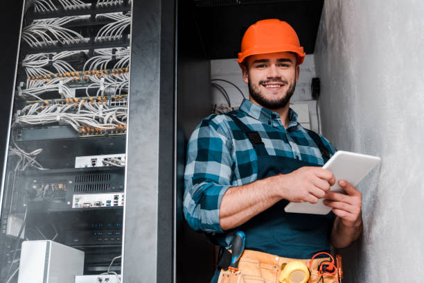 happy bearded technician in safety helmet holding digital tablet happy bearded technician in safety helmet holding digital tablet electrician smiling stock pictures, royalty-free photos & images