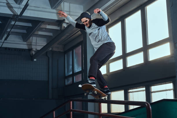 istock Young skateboarder performing a trick on mini ramp at skate park indoor. 1171131790