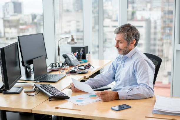 istock Focused business manager at his office checking some paperwork and looking at desktop screen 1171132272