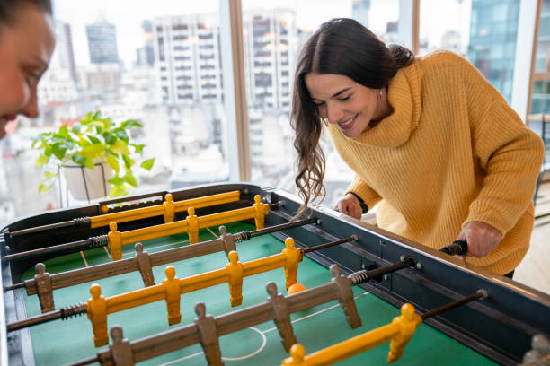 Beautiful woman having fun playing foosball at the office relaxing a while - New business concepts