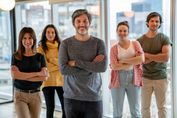 istock Confident business manager and his team standing at background all smiling at camera with arms crossed 1171132437