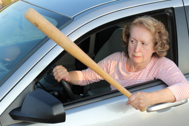 Angry mature female driver holding baseball bat