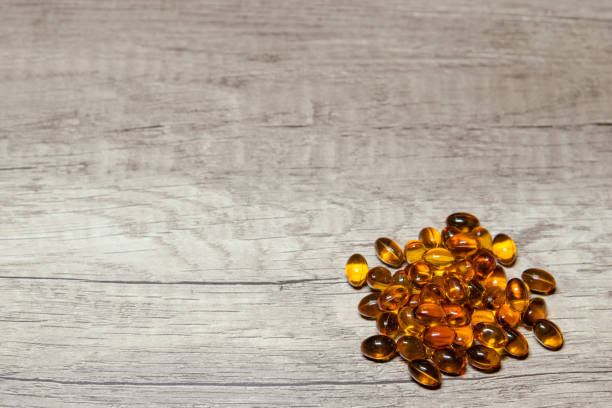 browm мягкая желатиновая капсула на деревянном полу. - fish oil coq10 vitamin e cod liver oil стоковые фото и изображения