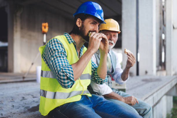 istock Happy mature and young engineer, architect, worker sitting at building site and resting 1171141404