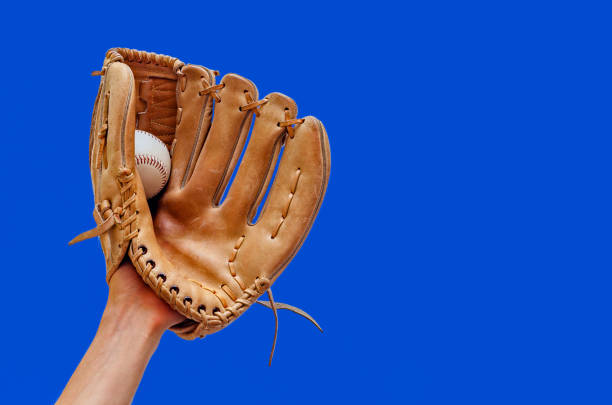istock Hand in a leather baseball glove caught a ball on a blue background. 1171142206