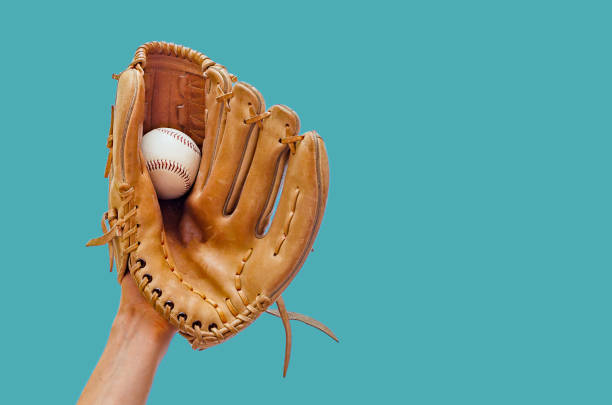 hand in einem leder baseballhandschuh einen ball auf einem grünen hintergrund - baseball glove stock-fotos und bilder