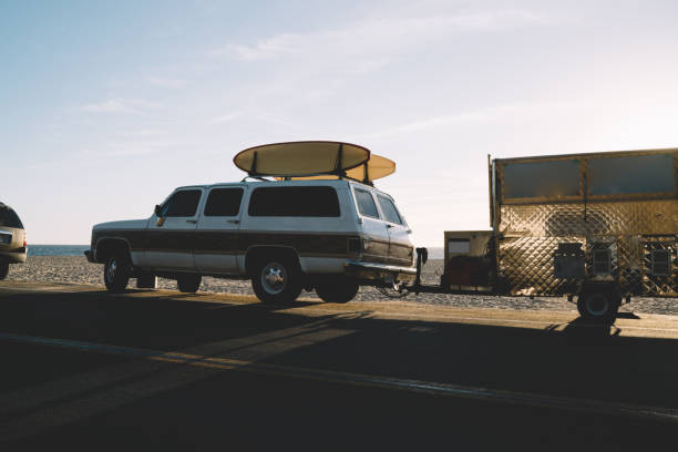 istock Old fashioned car transporting longboards for active hobby on ocean shore during summer vacation, surfers truck automobile with equipment for sport leisure parked near sea coast on asphalt road 1171143167