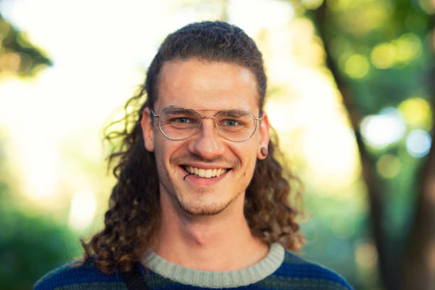 Portrait of handsome young man wearing eyeglasses looking at camera. Pierced young men in the park.