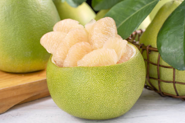 istock Fresh peeled pomelo, grapefruit, shaddock with green leaf on bright wooden plank table. Seasonal fruit near mid-autumn festival. 1171149857